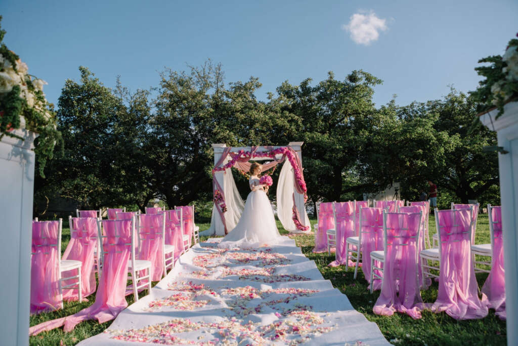 Beautiful outdoor wedding ceremony aisle decorated with pink drape